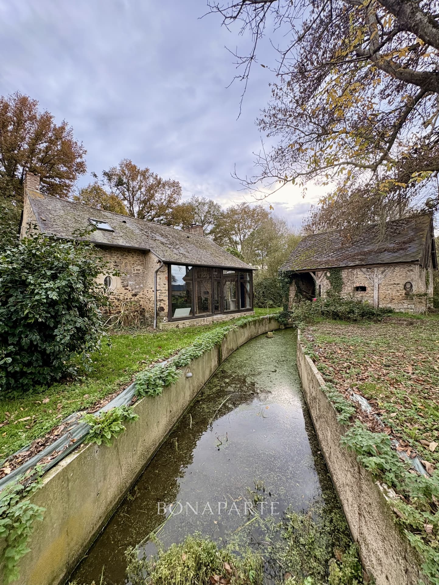 Ancien moulin entouré de verdure et de son fleuve
