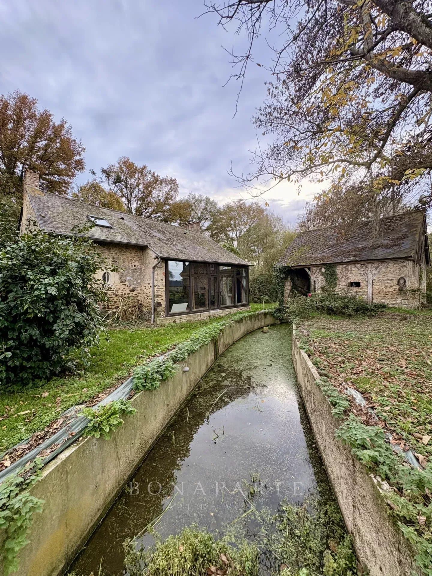 Ancien moulin entouré de verdure et de son fleuve
